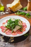 Vleescarpaccio met arugula en parmezaanse kaaskaas op witte plaat stock afbeelding Vleescarpaccio met arugula en parmezaanse kaaskaas op witte plaat stock afbeelding