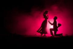 Você casar-me-á? Silhueta do homem novo que fica no joelho e que faz a proposta para sua menina bonita na praia contra t escuro fotografia de stock Você casar-me-á? Silhueta do homem novo que fica no joelho e que faz a proposta para sua menina bonita na praia contra t escuro fotografia de stock