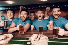 Voetbalventilators die op het spel het drinken bier letten en het eten bij sportenbar stock fotografie Voetbalventilators die op het spel het drinken bier letten en het eten bij sportenbar stock fotografie