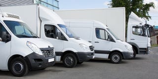 Voitures blanches de van trucks de service de distribution devant l'entrepôt d'usine image libre de droits Voitures blanches de van trucks de service de distribution devant l'entrepôt d'usine image libre de droits