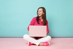 Volledig lengteportret van jonge vrouw in het roze witte de broek van de overhemdsblouse zitten op vloer die laptop PC met behulp royalty-vrije stock afbeelding Volledig lengteportret van jonge vrouw in het roze witte de broek van de overhemdsblouse zitten op vloer die laptop PC met behulp royalty-vrije stock afbeelding