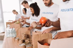 Volontari che mettono alimento e le bevande nelle borse fotografia stock libera da diritti Volontari che mettono alimento e le bevande nelle borse fotografia stock libera da diritti