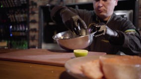 Volwassen chef-kok die groenten in grote aluminiumkom mengen met hand op de achtergrond Plaat met vissenstuk in de voorgrond stock footage Volwassen chef-kok die groenten in grote aluminiumkom mengen met hand op de achtergrond Plaat met vissenstuk in de voorgrond stock footage