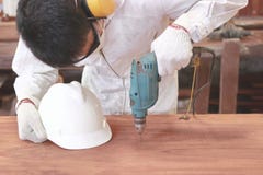 Vooraanzicht van jonge Aziatische arbeider die met veiligheid elektrische boor werken aan houten raad in timmerwerkworkshop stock afbeelding Vooraanzicht van jonge Aziatische arbeider die met veiligheid elektrische boor werken aan houten raad in timmerwerkworkshop stock afbeelding