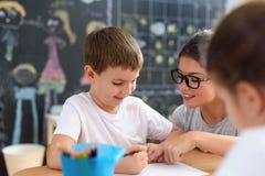 Vorschullehrer, der das intelligente Kind lernt zu schreiben und zu zeichnen betrachtet stockbild Vorschullehrer, der das intelligente Kind lernt zu schreiben und zu zeichnen betrachtet stockbild