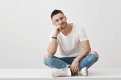 Vous ennuyeux ainsi Le studio a tiré du type non rasé caucasien attirant en verres, se reposant avec les jambes croisées sur le p photographie stock Vous ennuyeux ainsi Le studio a tiré du type non rasé caucasien attirant en verres, se reposant avec les jambes croisées sur le p photographie stock