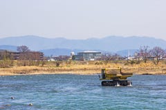 Vrachtwagen en het Uitbaggeren steen in rivier Katsura voor om water te maken stromen het ` s gemakkelijk in Kyoto stock afbeelding Vrachtwagen en het Uitbaggeren steen in rivier Katsura voor om water te maken stromen het ` s gemakkelijk in Kyoto stock afbeelding