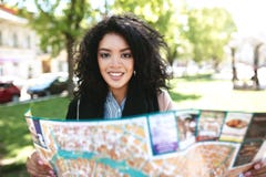 Vrij Afrikaans Amerikaans meisje die vreugdevol in camera met kaart in handen kijken Koel meisje die zich bij straat en het zoeke royalty-vrije stock foto's Vrij Afrikaans Amerikaans meisje die vreugdevol in camera met kaart in handen kijken Koel meisje die zich bij straat en het zoeke royalty-vrije stock foto's