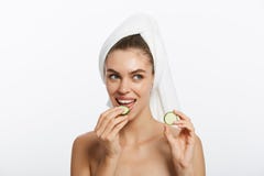 Vrij jong natuurlijk meisje die met perfecte schone huid camera bekijken die komkommerplak over witte achtergrond eten gezichts stock foto's Vrij jong natuurlijk meisje die met perfecte schone huid camera bekijken die komkommerplak over witte achtergrond eten gezichts stock foto's