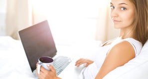 Vrij jonge vrouw met laptop in bed en het genieten van een van kop thee Royalty-vrije Stock Afbeelding Vrij jonge vrouw met laptop in bed en het genieten van een van kop thee Royalty-vrije Stock Afbeelding