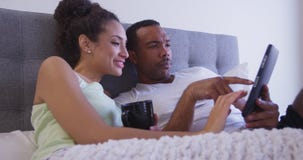 Vroeg ochtendpaar die tabletcomputer bekijken in bed en het drinken koffie slo-Mo royalty-vrije stock afbeeldingen Vroeg ochtendpaar die tabletcomputer bekijken in bed en het drinken koffie slo-Mo royalty-vrije stock afbeeldingen