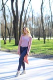 Vrolijk meisje die in park rusten en lange lichtrose sweater dragen Stock Afbeelding Vrolijk meisje die in park rusten en lange lichtrose sweater dragen Stock Afbeelding
