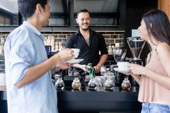 Vrolijke jonge barman die het koffiezetapparaat schoonmaken terwijl het spreken stock fotografie Vrolijke jonge barman die het koffiezetapparaat schoonmaken terwijl het spreken stock fotografie