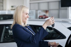 Vrolijke jonge vrouw die nieuwe autosleutels in autowinkel ontvangen stock foto Vrolijke jonge vrouw die nieuwe autosleutels in autowinkel ontvangen stock foto