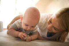 Vrolijke moeder op bed met haar babyjongen stock fotografie Vrolijke moeder op bed met haar babyjongen stock fotografie