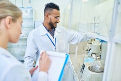 Vrolijke onderzoeker en zijn medewerker die laboratoriummateriaal met behulp van royalty-vrije stock afbeelding Vrolijke onderzoeker en zijn medewerker die laboratoriummateriaal met behulp van royalty-vrije stock afbeelding
