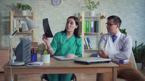 Vrouw de arts met in hand röntgenstraal communiceert met de patiënt stock footage Vrouw de arts met in hand röntgenstraal communiceert met de patiënt stock footage