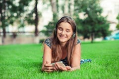 Vrouw die aan mobiele telefoon kijken die in in openlucht het liggen glimlachen stock foto Vrouw die aan mobiele telefoon kijken die in in openlucht het liggen glimlachen stock foto