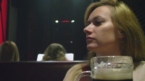 Vrouw die donker vers bier van een glas in een nachtclub drinken stock videobeelden Vrouw die donker vers bier van een glas in een nachtclub drinken stock videobeelden