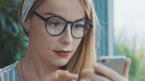 Vrouw die door beelden op smartphone in koffie kijken Mooi jong en meisje die dromen glimlachen stock videobeelden Vrouw die door beelden op smartphone in koffie kijken Mooi jong en meisje die dromen glimlachen stock videobeelden