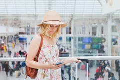 Vrouw die in luchthaven mobiele telefoon, reizigerssmartphone app controleren stock fotografie Vrouw die in luchthaven mobiele telefoon, reizigerssmartphone app controleren stock fotografie