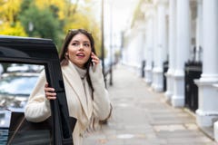 Vrouw die op haar mobiele telefoon spreken terwijl de stappen van een zwarte cabine in Londen, het UK taxi?en stock afbeeldingen Vrouw die op haar mobiele telefoon spreken terwijl de stappen van een zwarte cabine in Londen, het UK taxi?en stock afbeeldingen
