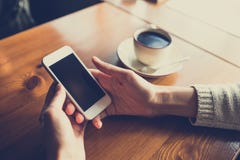 Vrouw die smartphone op houten lijst in koffie gebruiken stock afbeelding Vrouw die smartphone op houten lijst in koffie gebruiken stock afbeelding