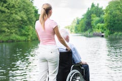 Vrouw met Haar Gehandicapte Vader On Wheelchair Looking bij Meer royalty-vrije stock fotografie Vrouw met Haar Gehandicapte Vader On Wheelchair Looking bij Meer royalty-vrije stock fotografie