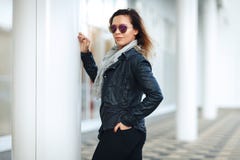 Vrouw in zonglazen een zwart leerjasje, zwarte jeans die voor weerspiegelde vensters stellen Vrouwelijk manierconcept openlucht royalty-vrije stock foto Vrouw in zonglazen een zwart leerjasje, zwarte jeans die voor weerspiegelde vensters stellen Vrouwelijk manierconcept openlucht royalty-vrije stock foto