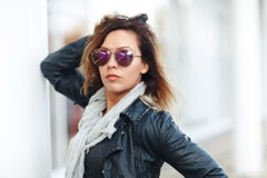 Vrouw in zonglazen een zwart leerjasje, zwarte jeans die voor weerspiegelde vensters stellen Vrouwelijk manierconcept openlucht stock foto Vrouw in zonglazen een zwart leerjasje, zwarte jeans die voor weerspiegelde vensters stellen Vrouwelijk manierconcept openlucht stock foto
