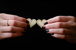 Vrouwelijke handen die twee houten harten op de zwarte achtergrond geven stock foto Vrouwelijke handen die twee houten harten op de zwarte achtergrond geven stock foto