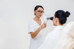 Vrouwelijke optometrist die met speciaal materiaal geduldige visie controleren bij oogkliniek royalty-vrije stock afbeelding Vrouwelijke optometrist die met speciaal materiaal geduldige visie controleren bij oogkliniek royalty-vrije stock afbeelding