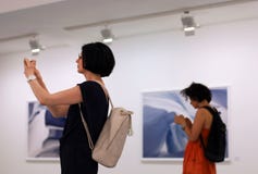 Vrouwen bij fotoexhition smartphones, mobiele apparaten en sociale netwerkverslaving die gebruiken royalty-vrije stock foto Vrouwen bij fotoexhition smartphones, mobiele apparaten en sociale netwerkverslaving die gebruiken royalty-vrije stock foto