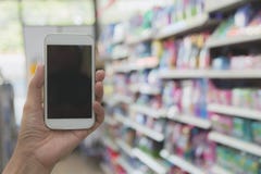 Vrouwenhand die slimme telefoon in supermarkt het winkelen houden Royalty-vrije Stock Fotografie Vrouwenhand die slimme telefoon in supermarkt het winkelen houden Royalty-vrije Stock Fotografie
