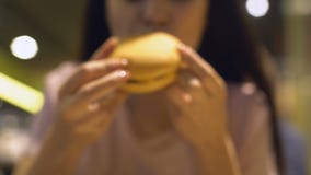 Vrouwenhanden die smakelijke cheeseburger van lijst, ongezonde maaltijd, zwaarlijvigheidsrisico nemen stock footage Vrouwenhanden die smakelijke cheeseburger van lijst, ongezonde maaltijd, zwaarlijvigheidsrisico nemen stock footage