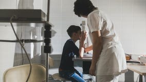 Vrouwenoptometrist die pre adolescentiejongens` s ogen in oftalmologiekliniek onderzoeken stock afbeelding Vrouwenoptometrist die pre adolescentiejongens` s ogen in oftalmologiekliniek onderzoeken stock afbeelding