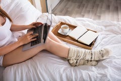 Vrouwenzitting op Bed die aan Laptop werken stock afbeelding Vrouwenzitting op Bed die aan Laptop werken stock afbeelding