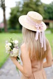 Vue arrière de jeune fille blonde dans les combinaisons et le chapeau de gouache avec des fleurs image stock Vue arrière de jeune fille blonde dans les combinaisons et le chapeau de gouache avec des fleurs image stock