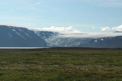 Vue au-dessus de plaine verte plate large sur le glacier sortant entre un espace des montagnes - Islande image libre de droits Vue au-dessus de plaine verte plate large sur le glacier sortant entre un espace des montagnes - Islande image libre de droits