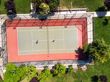 Vue aérienne de bourdon de court de tennis dans le jardin avec des joueurs jouant le tennis photographie stock Vue aérienne de bourdon de court de tennis dans le jardin avec des joueurs jouant le tennis photographie stock