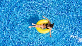 Vue aérienne de la jeune natation de femme de brune sur le grand jaune gonflable dans la piscine Vue supérieure de dame mince dét photo stock Vue aérienne de la jeune natation de femme de brune sur le grand jaune gonflable dans la piscine Vue supérieure de dame mince dét photo stock
