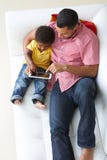 Vue aérienne de père And Son On Sofa Using Digital Tablet images stock Vue aérienne de père And Son On Sofa Using Digital Tablet images stock