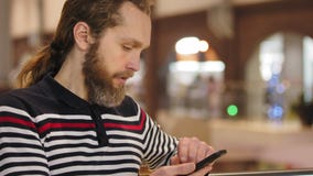 Homme sérieux avec des cheveux longs et une barbe sur une plage de