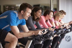 Vue de côté d'une classe de rotation sur des vélos d'exercice à un gymnase photographie stock libre de droits Vue de côté d'une classe de rotation sur des vélos d'exercice à un gymnase photographie stock libre de droits