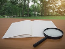 Vue de carnet et de loupe sur la table en bois avec le fond vert d'arbre photos libres de droits Vue de carnet et de loupe sur la table en bois avec le fond vert d'arbre photos libres de droits