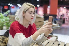 Vue de côté d'une jeune belle femme prenant un selfie dans une barre photographie stock libre de droits Vue de côté d'une jeune belle femme prenant un selfie dans une barre photographie stock libre de droits