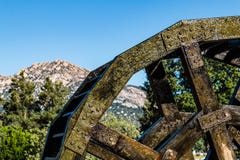 Vue de côté de roue en bois et en métal d'eau avec des montagnes photo libre de droits Vue de côté de roue en bois et en métal d'eau avec des montagnes photo libre de droits