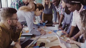 Vue en gros plan de la jeune équipe d'affaires travaillant ensemble près de la table, faisant un brainstorm Deux équipe le poing banque de vidéos Vue en gros plan de la jeune équipe d'affaires travaillant ensemble près de la table, faisant un brainstorm Deux équipe le poing banque de vidéos