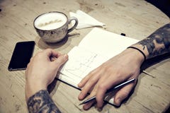 Vue en gros plan des mains masculines avec la vue supérieure de carnet et de café Photo stock Vue en gros plan des mains masculines avec la vue supérieure de carnet et de café Photo stock