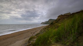 Vue le long de la c?te de Dorset de la plage pr?s d'Eype un jour venteux avec la longue exposition lissant la mer et brouillant l image stock Vue le long de la c?te de Dorset de la plage pr?s d'Eype un jour venteux avec la longue exposition lissant la mer et brouillant l image stock